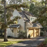 Rumah kayu bergaya Barat dengan atap miring dan garasi di area perumahan yang dikelilingi pepohonan