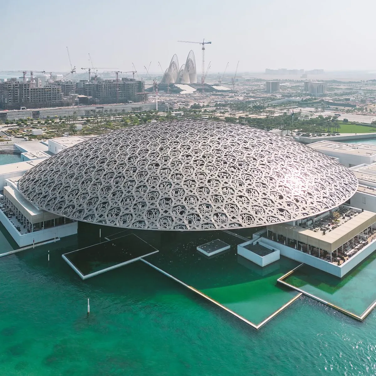 Tampilan udara Louvre Abu Dhabi di Uni Emirat Arab, menampilkan kubah geometris yang rumit dan tampaknya melayang di atas air