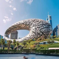 Museum futuristik berbentuk oval berlubang dengan kaligrafi Arab di Museum of the Future, tampak seperti objek CGI di tengah kota modern Dubai.