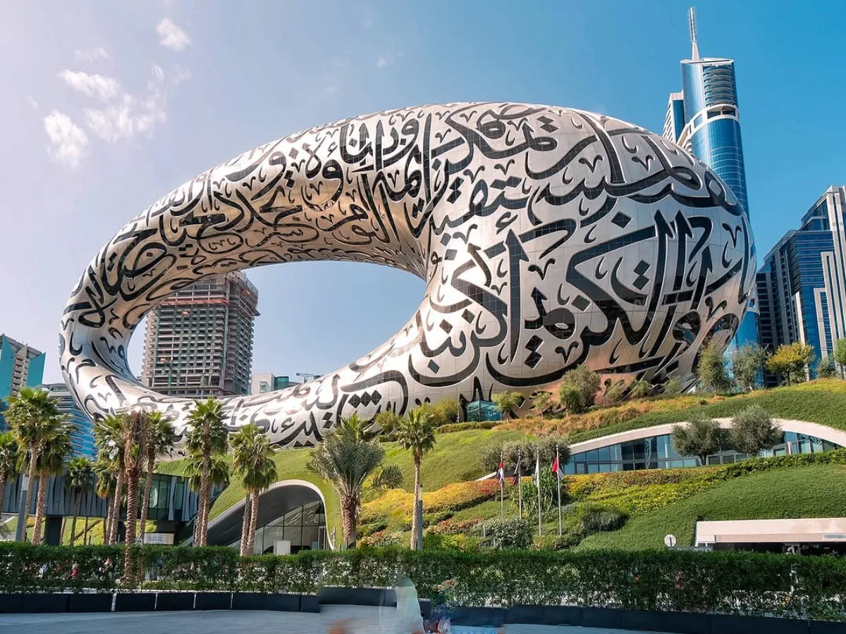 Museum futuristik berbentuk oval berlubang dengan kaligrafi Arab di Museum of the Future, tampak seperti objek CGI di tengah kota modern Dubai.