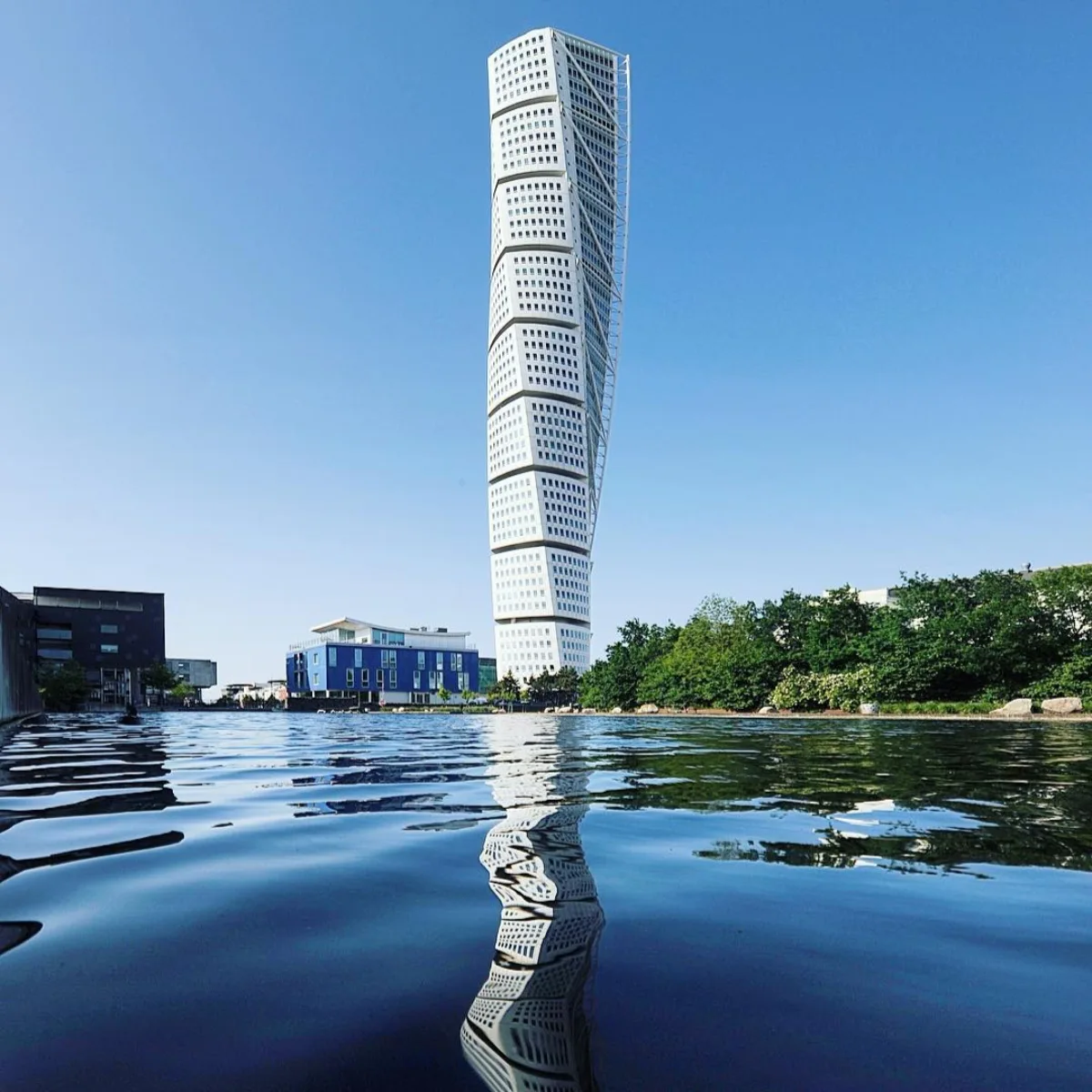 pencakar langit melintir Turning Torso di Swedia, berwarna putih, berdiri di tepi air dengan pantulan air yang jernih