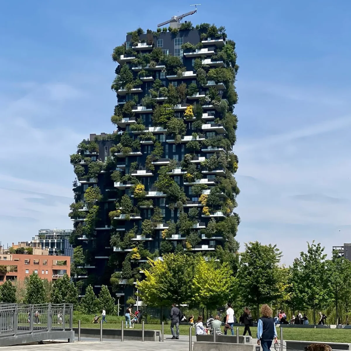 Gedung pencakar langit Bosco Verticale di Milan Italia yang unik dengan pepohonan hijau rimbun tumbuh di setiap balkonnya serta area taman dan pejalan kaki di bagian depan