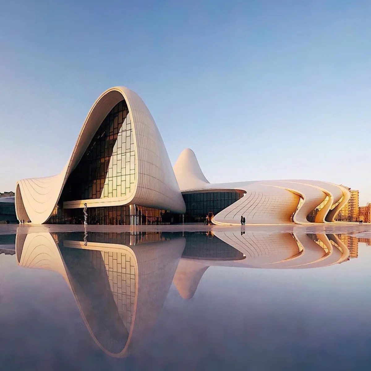 bentuk putih bergelombang dan mengalir dari Heydar Aliyev Center di Azerbaijan dengan pantulan di kolam air