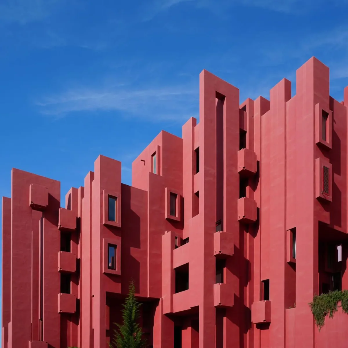 bagian luar apartemen La Muralla Roja yang berwarna merah muda cerah dengan bentuk geometris kaku dan tangga bersilang
