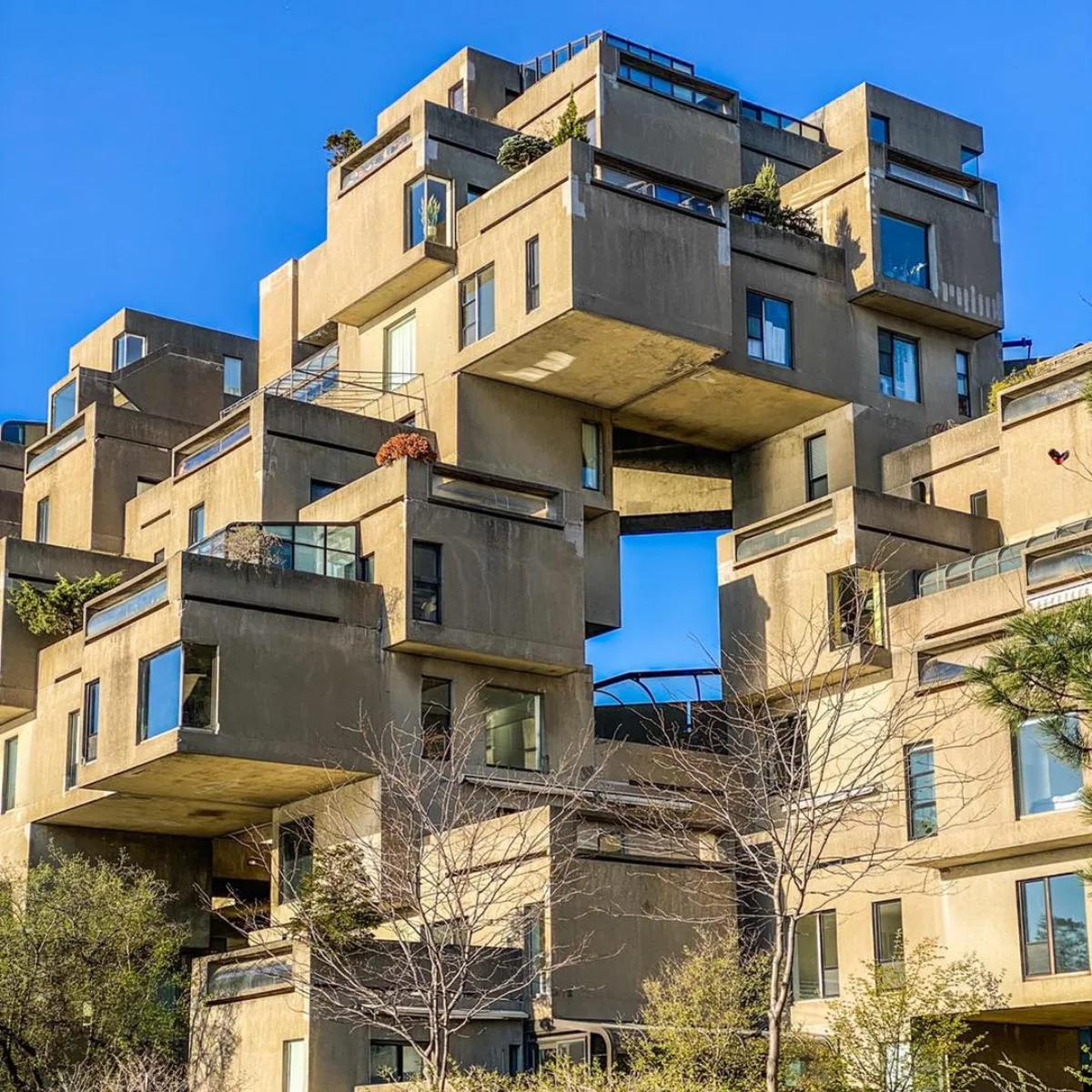 Habitat 67 kompleks apartemen yang terbuat dari susunan balok beton abu-abu yang bertumpuk secara asimetris dan tidak beraturan di bawah langit biru
