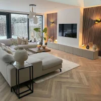 Contoh desain interior rumah modern minimalis dengan ruang tamu terbuka, sofa netral, lantai parket, dan aksen kayu.