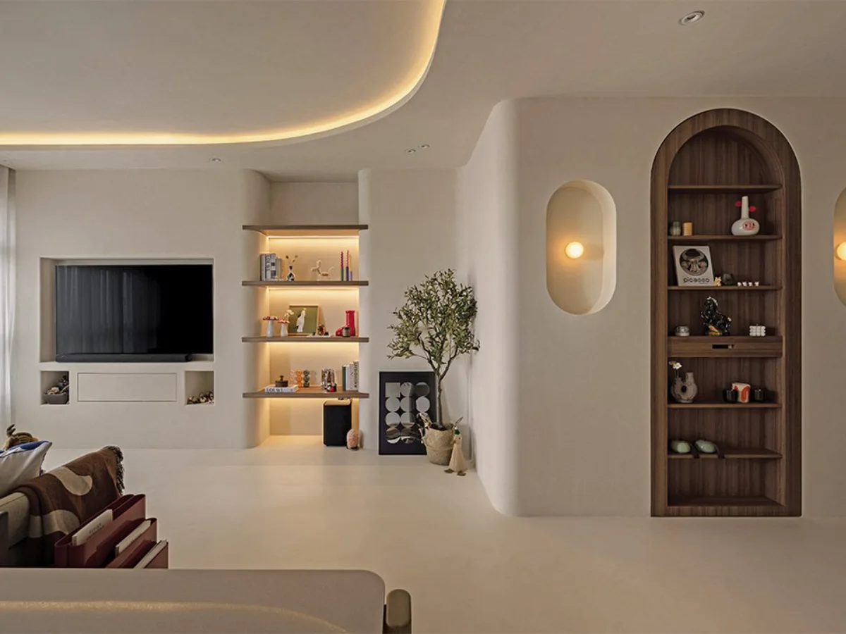 Desain interior Minimalis modern dengan rak dinding lengkung (arched niche), pencahayaan ambient yang lembut, dan dominasi warna krem bersih tanpa banyak dekorasi.