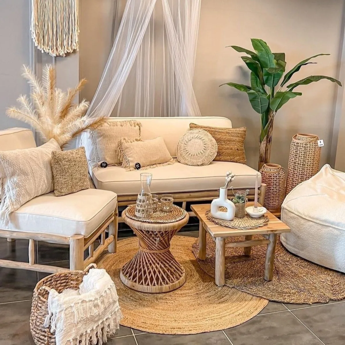 Inspirasi ruang tamu gaya Boho Chic yang menampilkan kursi rotan, bantal tekstur alami, hiasan dinding macrame, rumput pampas, dan nuansa warna krem yang hangat.