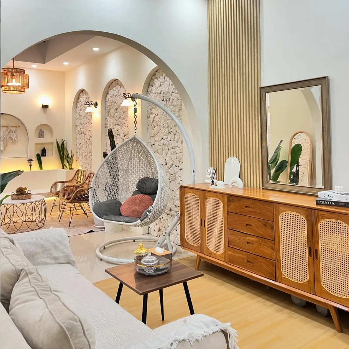 Ruang keluarga gaya Japandi yang memadukan panel kayu natural, furnitur rotan, kursi gantung estetik, dan nuansa warna earth tone yang hangat.