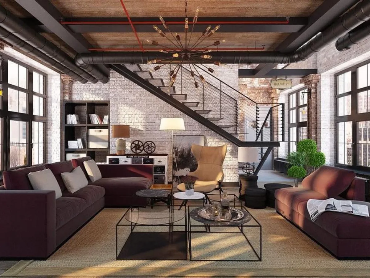 Ruang tamu bergaya industrial dengan dinding bata merah ekspos, pipa plafon hitam, tangga besi, dan sofa modern bernuansa gelap