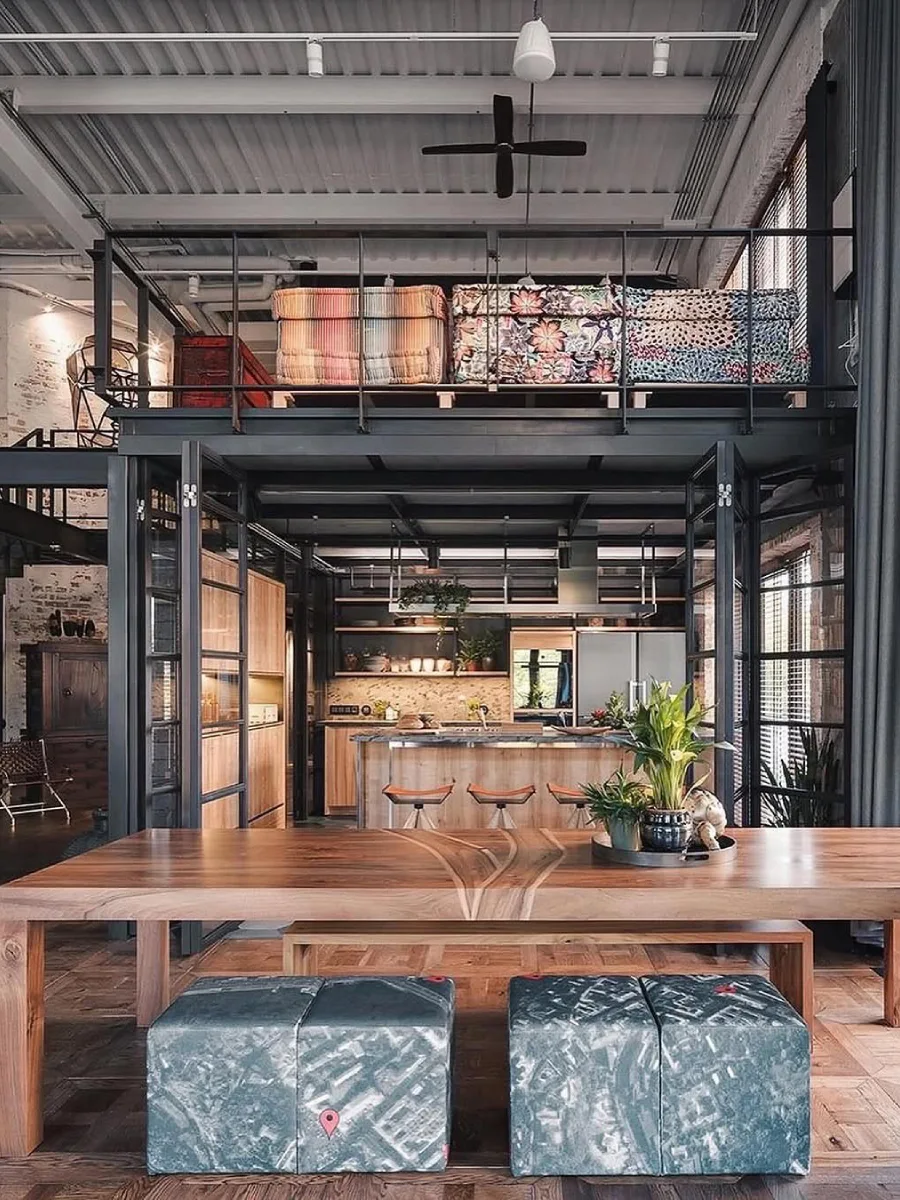 Dapur bernuansa industrial dengan pintu lipat kaca berbingkai besi hitam yang terletak tepat di bawah area mezzanine