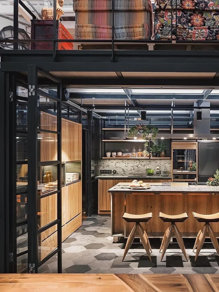 Kitchen island material kayu bergaya industrial dengan kursi bar unik, rak gantung besi hitam, dan lantai ubin heksagonal