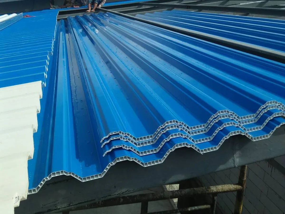 Dua pekerja bangunan sedang memasang lembaran atap UPVC berongga warna biru pada kerangka baja ringan