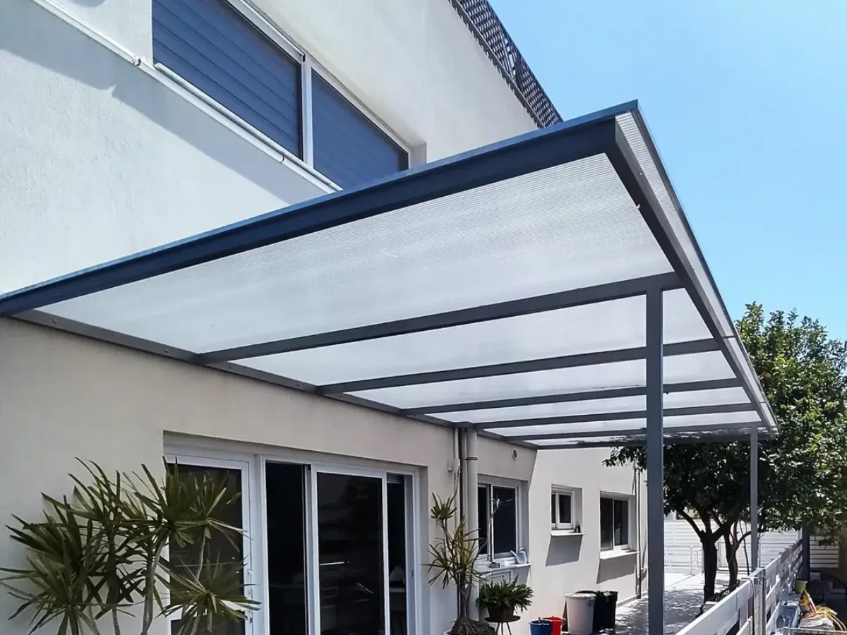 Kanopi atap polikarbonat datar dan semi transparan dengan rangka metal yang terpasang menaungi area teras rumah