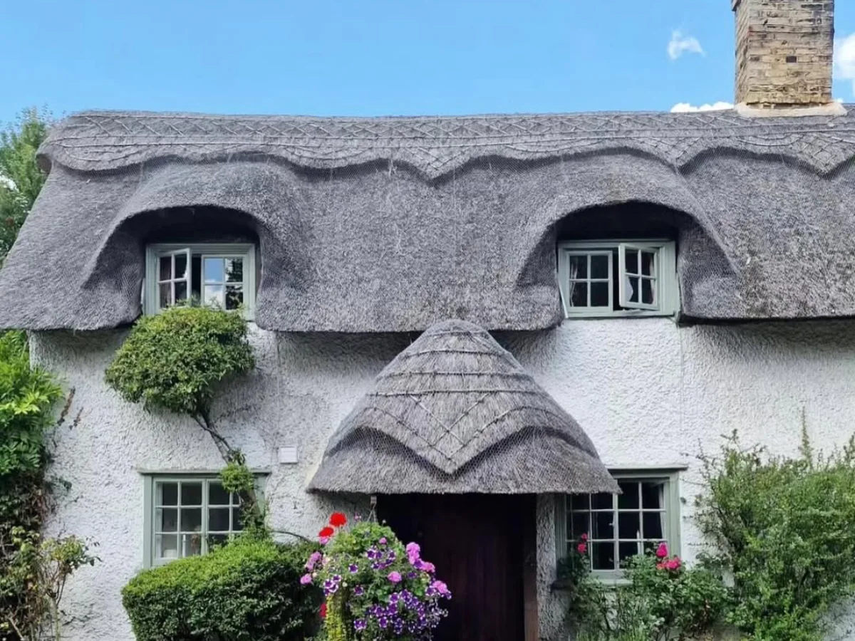 Rumah pondok bergaya klasik dengan atap tebal dari tumpukan jerami kering berwarna abu-abu kecokelatan yang unik
