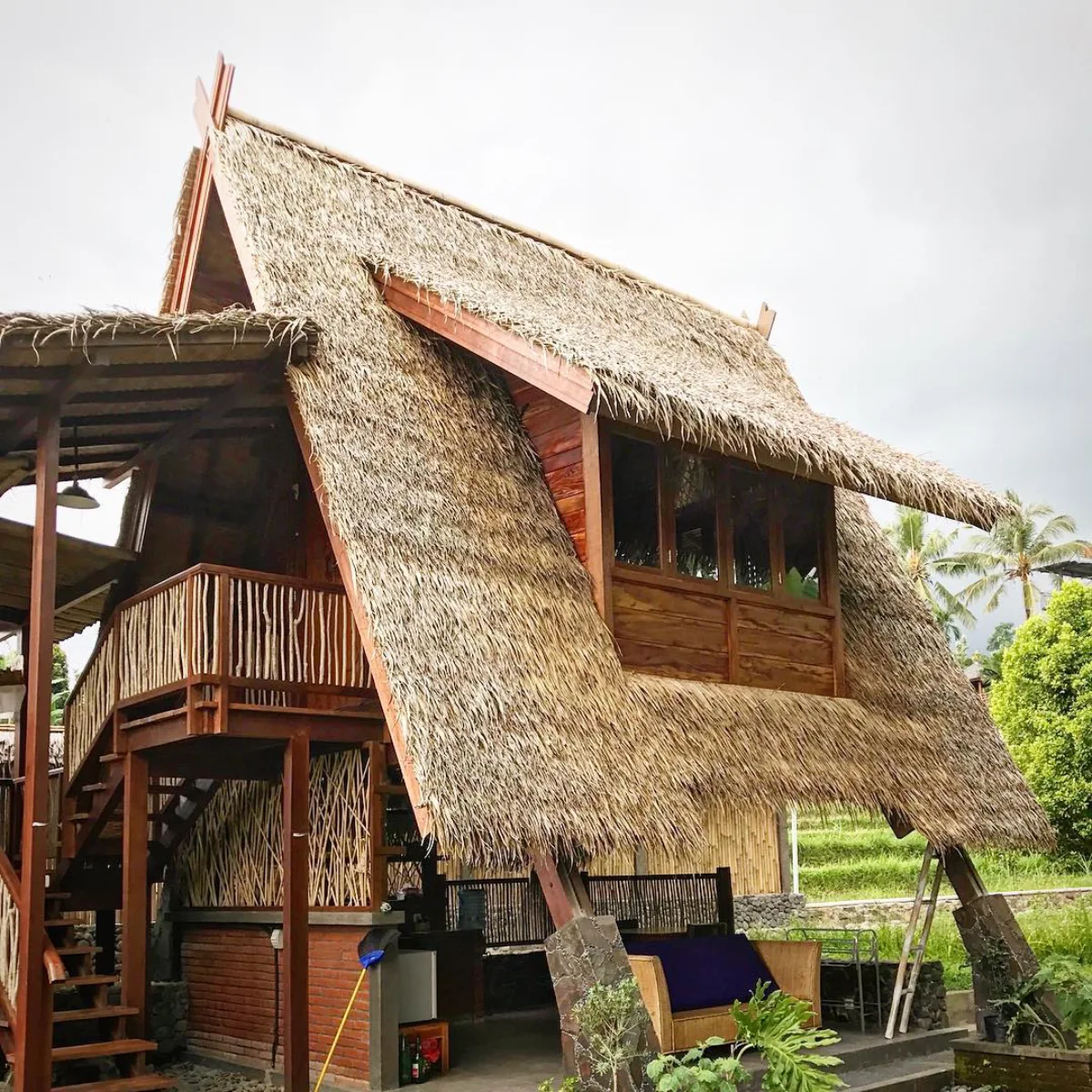 Rumah panggung tradisional dengan atap berbentuk segitiga yang terbuat dari susunan daun rumbia kering