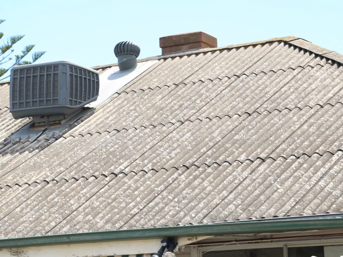 Atap rumah bergelombang yang terbuat dari lembaran material asbes berwarna abu-abu kusam