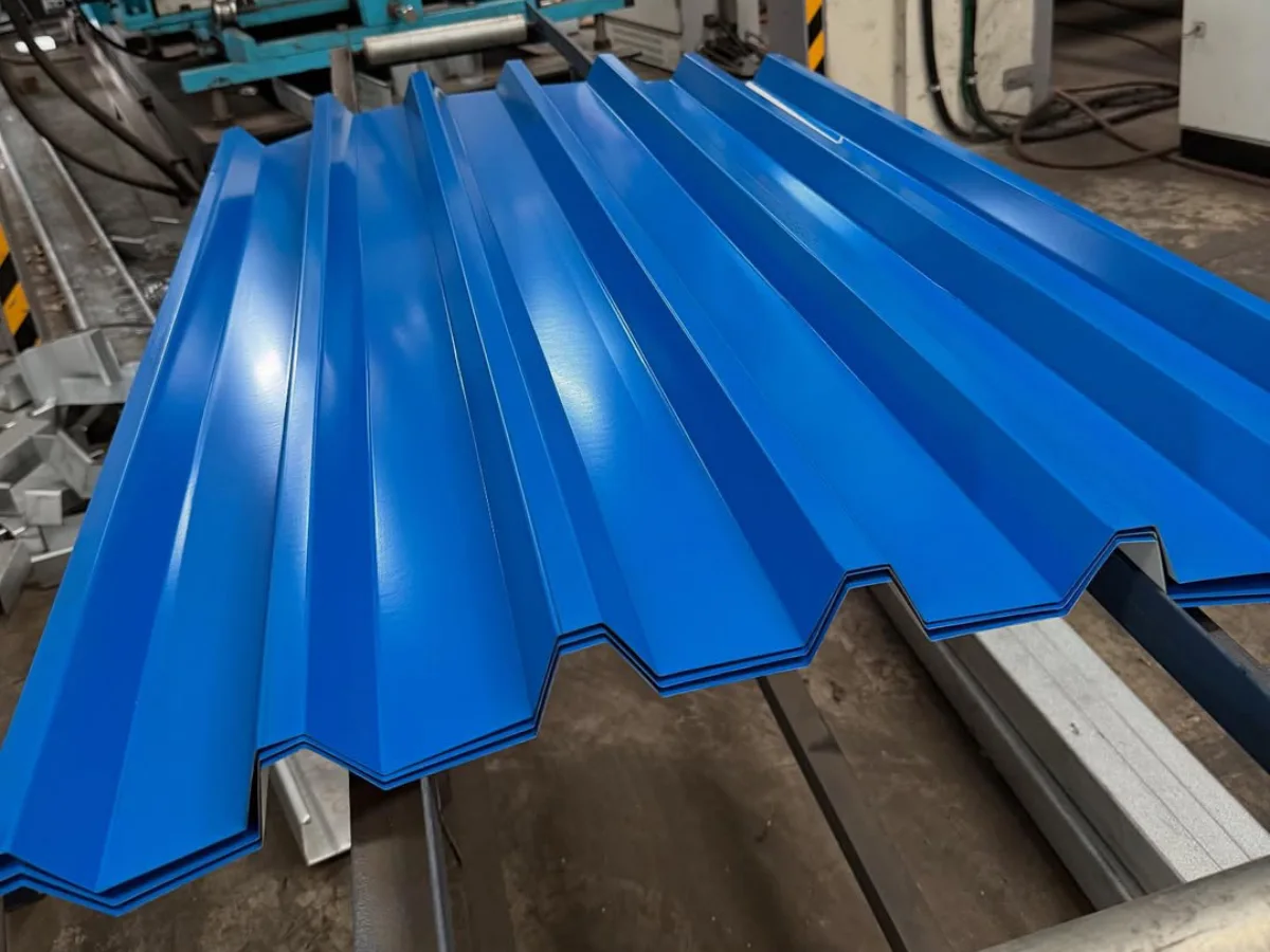 Lembaran atap spandek bergelombang warna biru cerah yang berada di atas mesin roll forming di dalam pabrik
