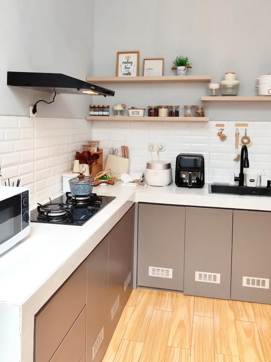 Dapur minimalis modern dengan backsplash bata putih, rak ambalan kayu terbuka, dan peralatan dapur yang tersusun rapi di atas meja dapur.