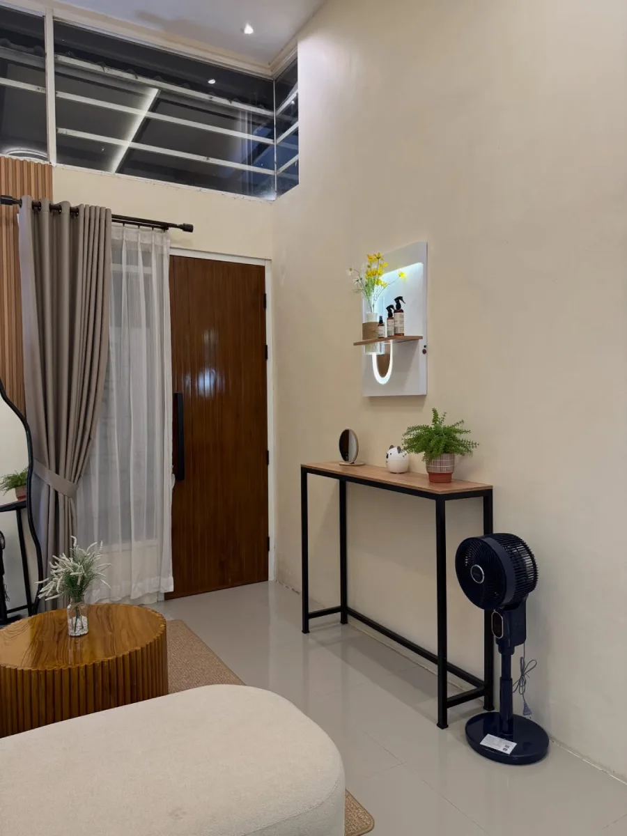 Area foyer atau lorong masuk rumah minimalis dengan meja konsol berangka besi hitam, dekorasi simpel, dan rak dinding putih berpenerangan LED.