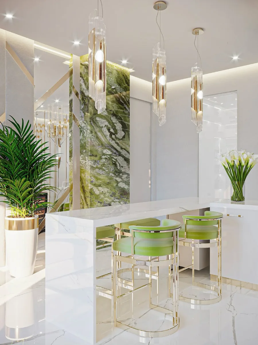 Area minibar dapur modern dengan meja marmer putih, kursi bar hijau beraksen emas, dan dinding latar marmer hijau yang mencolok