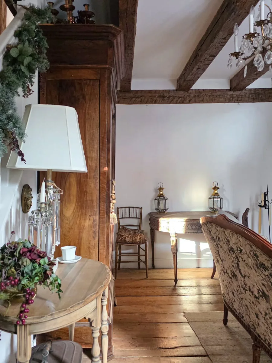 Sudut ruangan bernuansa rustic dengan lantai kayu papan lebar lampu meja kristal vintage dan meja konsol kayu berhiaskan dua lentera klasik