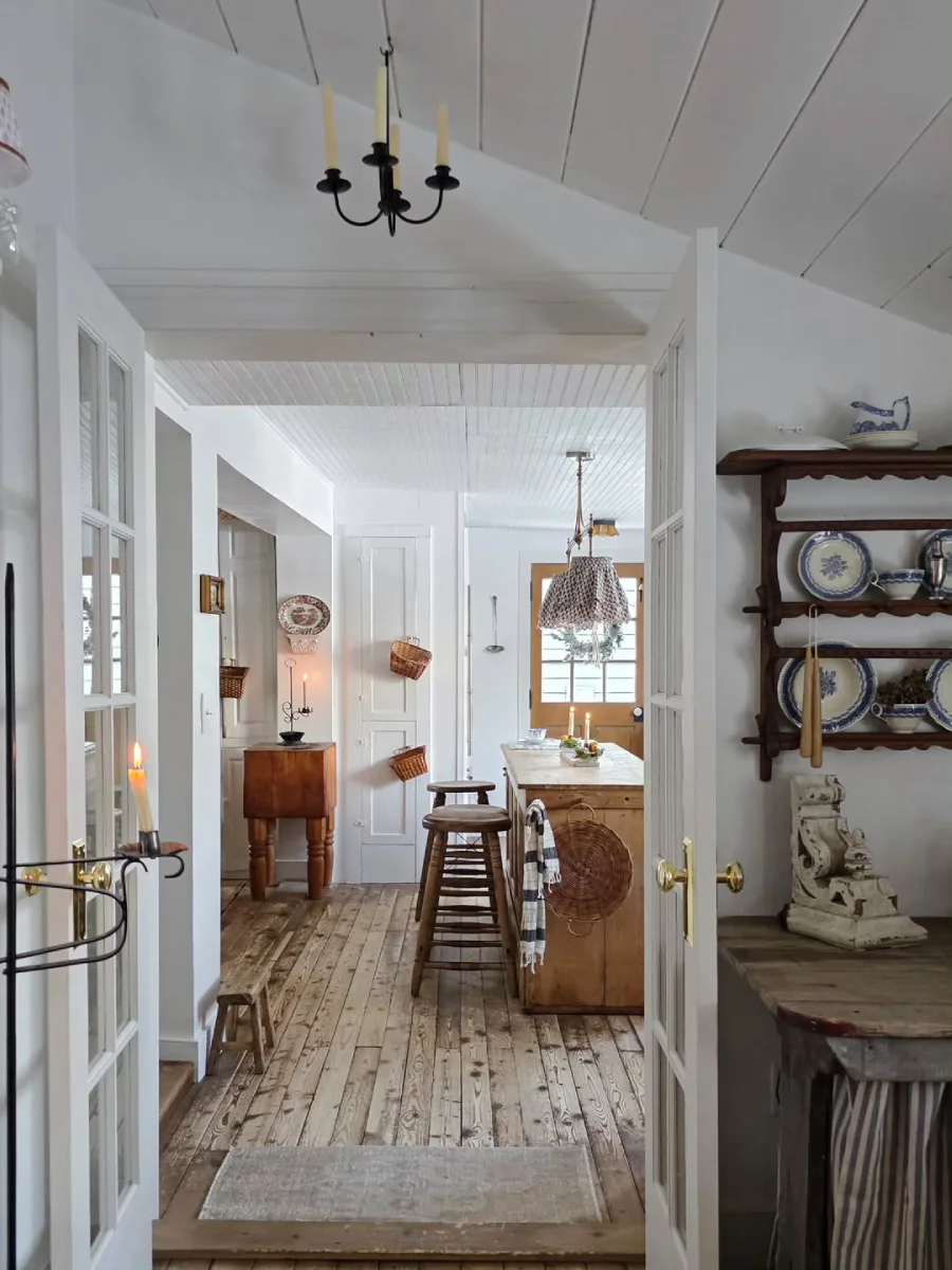 Interior dapur bernuansa rustic dilihat melalui pintu kaca ganda menampilkan lantai kayu bertekstur island dapur kayu alami dan rak piring dinding