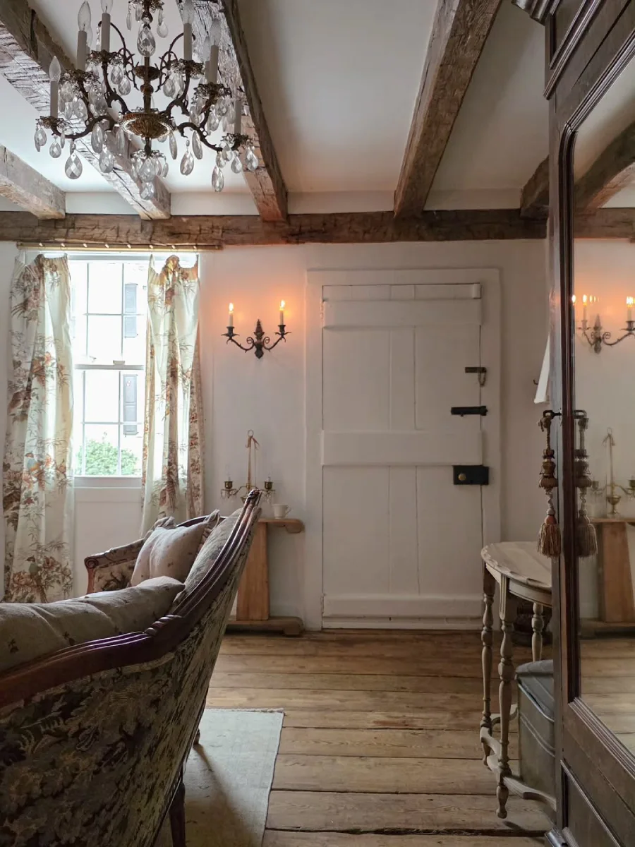 Sisi ruang tamu dengan pintu kayu putih solid bernuansa pedesaan tirai bermotif alam sofa klasik dan lemari kayu besar berpintu cermin