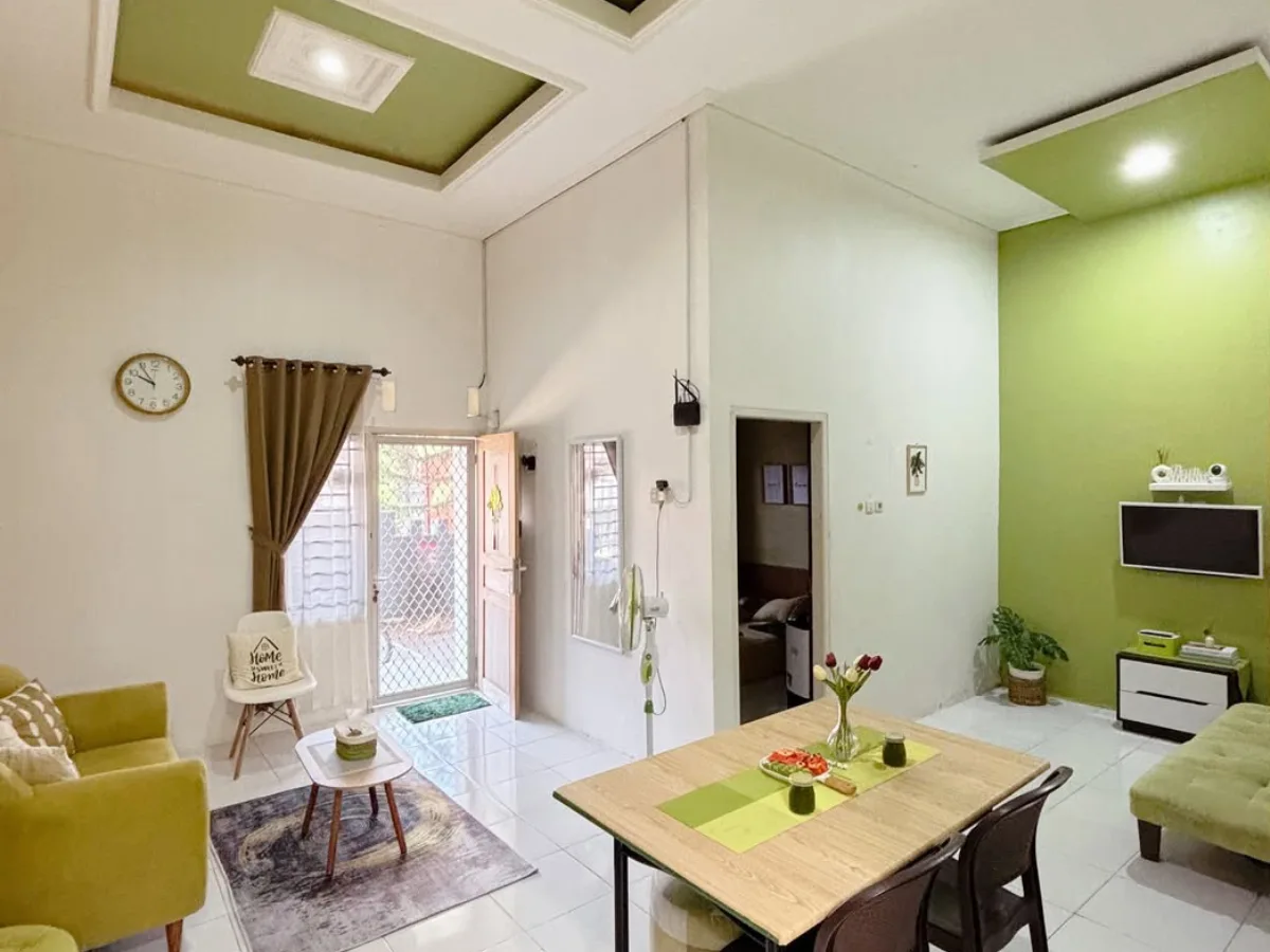 Interior rumah dengan warna cat hijau muda yang sejuk, ruang tamu dan ruang makan menyatu dengan pencahayaan terang dan suasana nyaman.