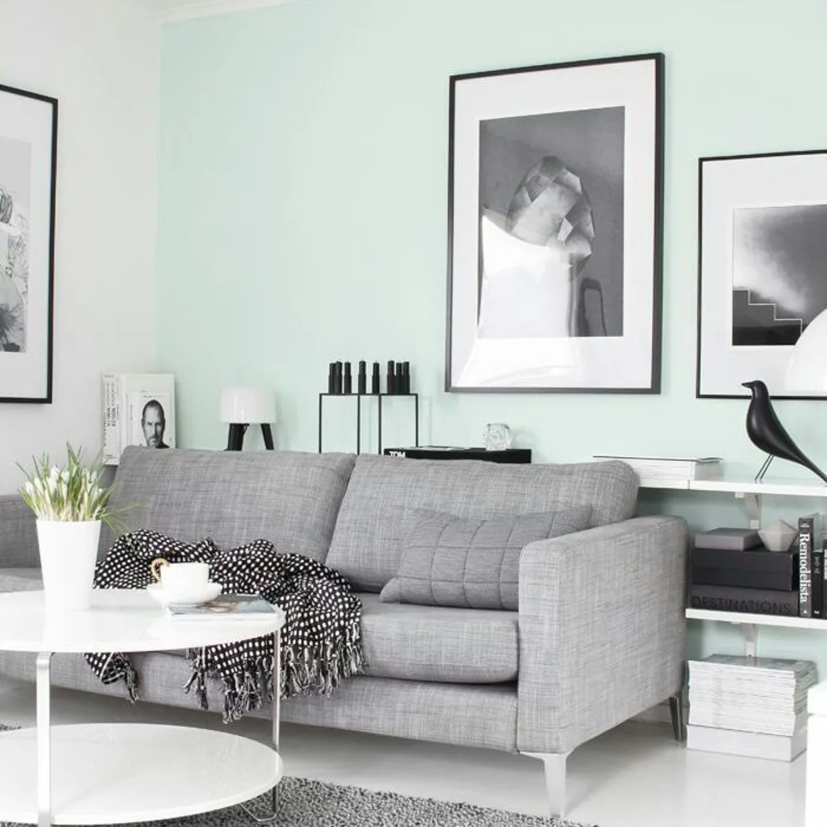 Desain ruang tamu scandinavian yang segar dengan dinding cat hijau mint, sofa abu-abu tekstur, dan galeri foto hitam putih.