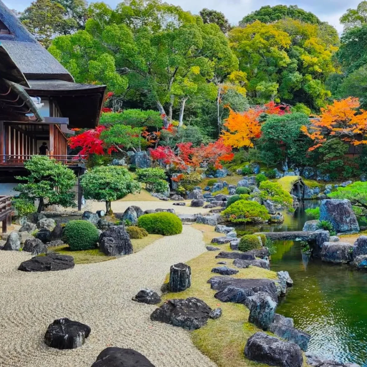 Taman Jepang dengan kombinasi batu besar, tanaman hijau rapi, dan jalur kerikil natural.