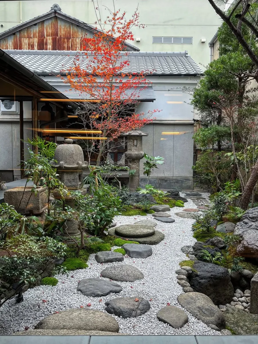 Taman Jepang sederhana dengan kerikil putih dan batu besar sebagai titik fokus.