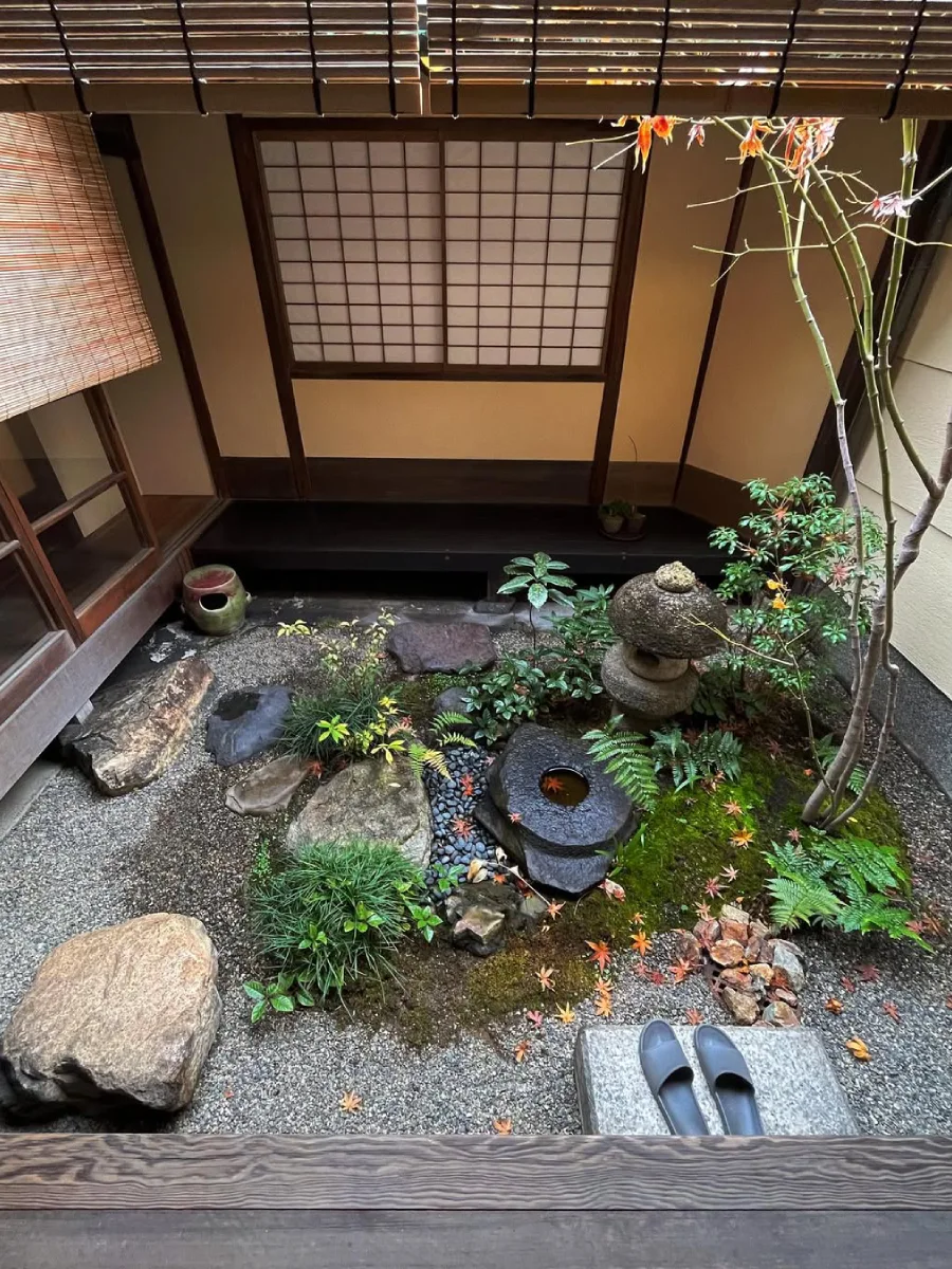 Taman Jepang bernuansa tradisional dengan kolam kecil, batu dekoratif, dan tanaman rimbun.
