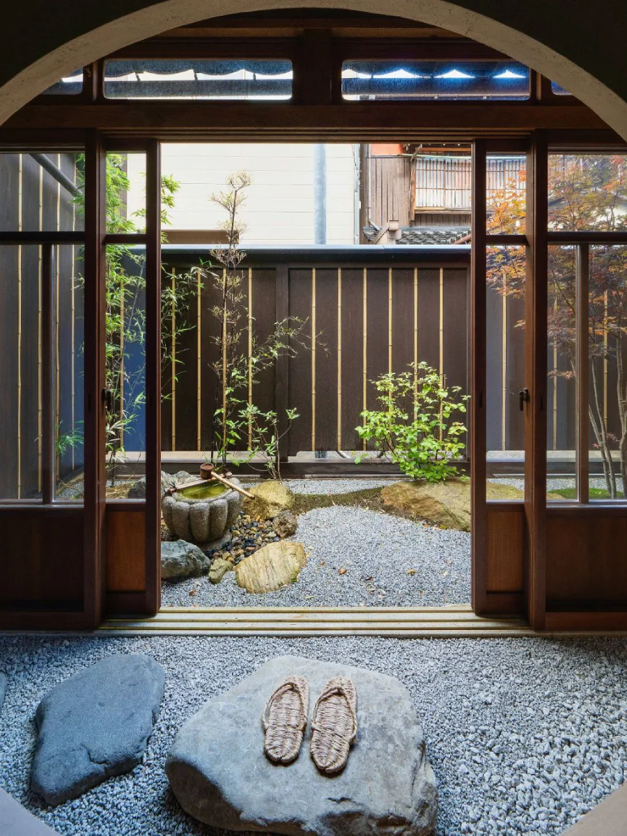 Taman Jepang dengan pohon kecil, batu pipih, dan jalur setapak yang tertata asimetris.