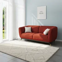Sofa dua dudukan berwarna merah bata dengan sofa minimalis di ruang tamu modern bernuansa terang, dilengkapi karpet krem dan cahaya alami dari jendela besar.