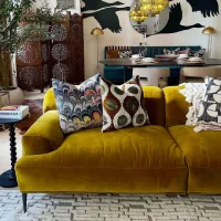 Sofa velvet warna kuning mustard dengan bantal motif di ruang tamu bergaya modern bohemian