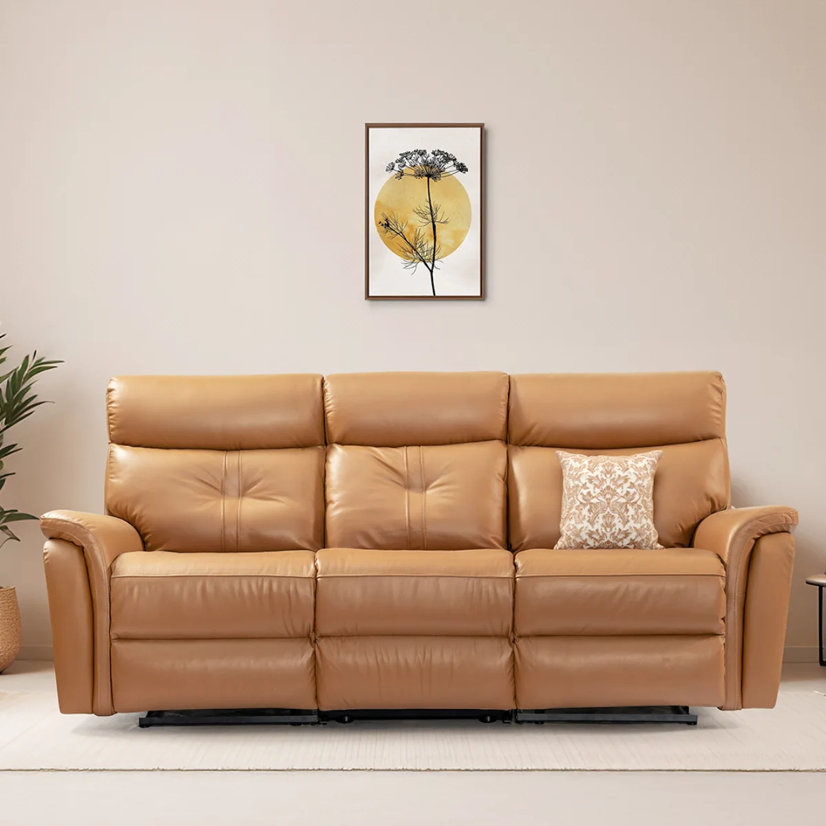 Sofa tiga dudukan berukuran besar yang mewah dengan material kulit asli berwarna cokelat tan, memiliki desain bantalan punggung dan dudukan yang sangat empuk khas kursi recliner, disempurnakan dengan sebuah bantal hias bermotif di sudutnya.
