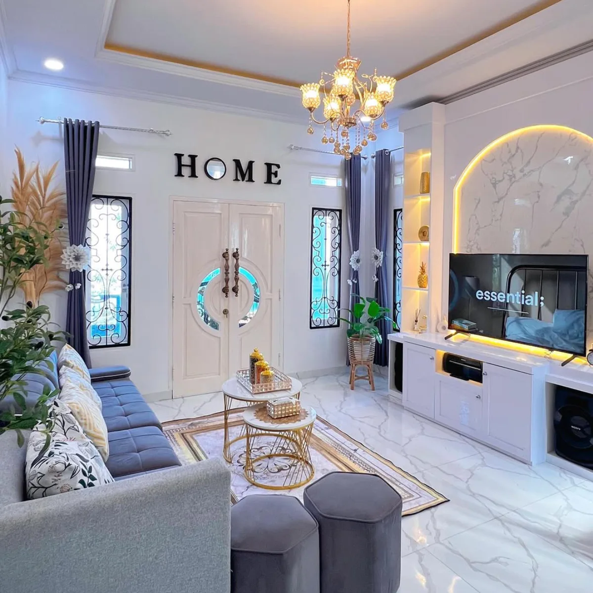 Desain ruang tamu mewah modern dengan lampu kristal emas, lantai marmer, dan dekorasi dinding tulisan HOME.