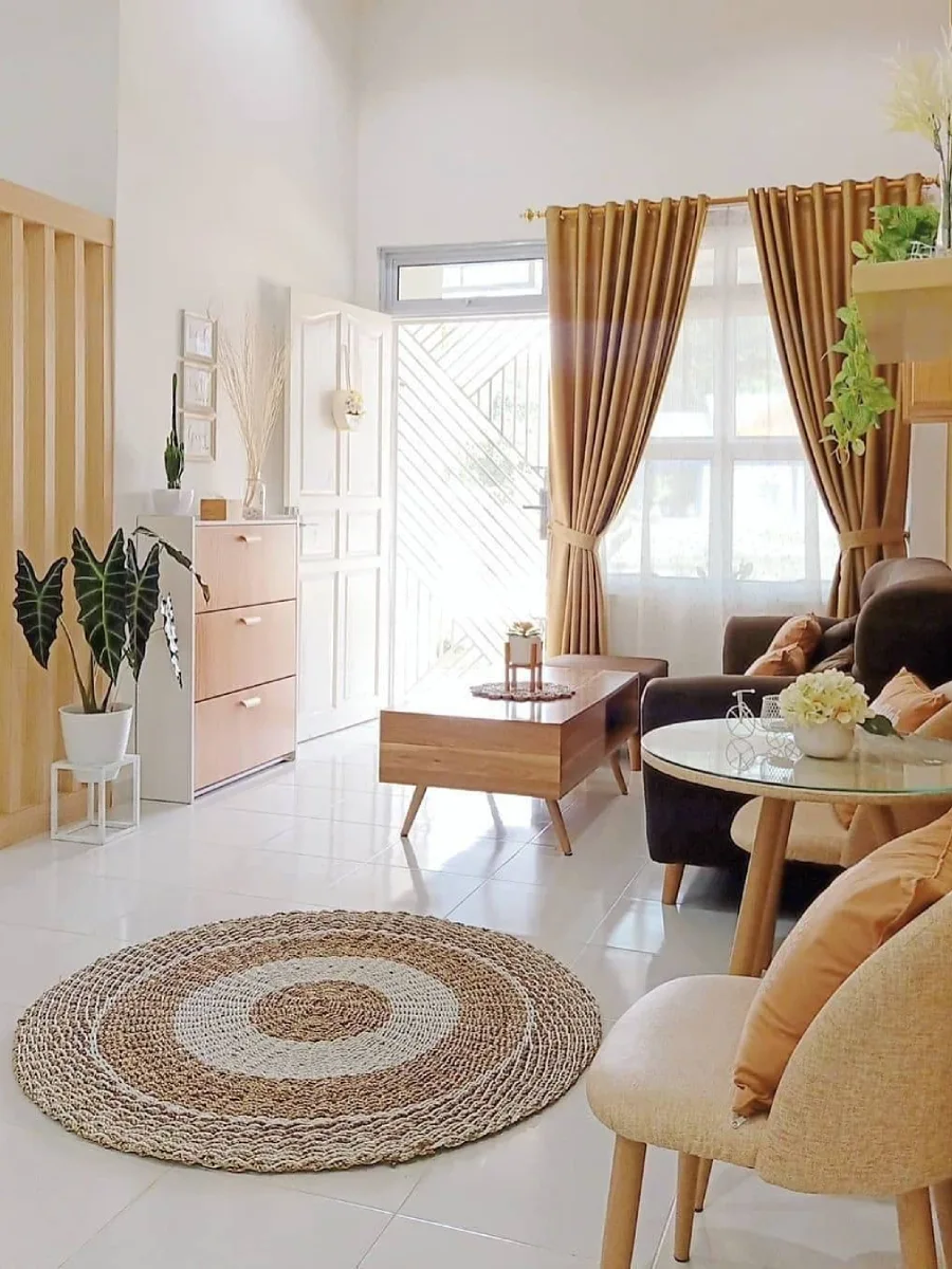 Penataan ruang tamu mungil dekat pintu masuk dengan partisi kayu minimalis dan karpet anyaman bulat.