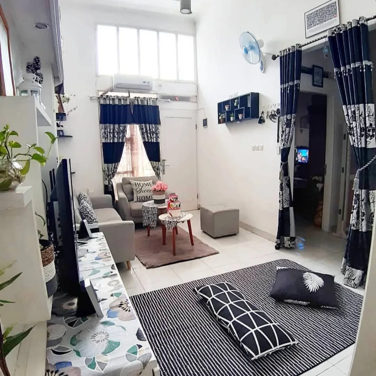 Desain ruang tamu minimalis monokrom dengan karpet motif garis hitam putih dan dekorasi dinding simpel.