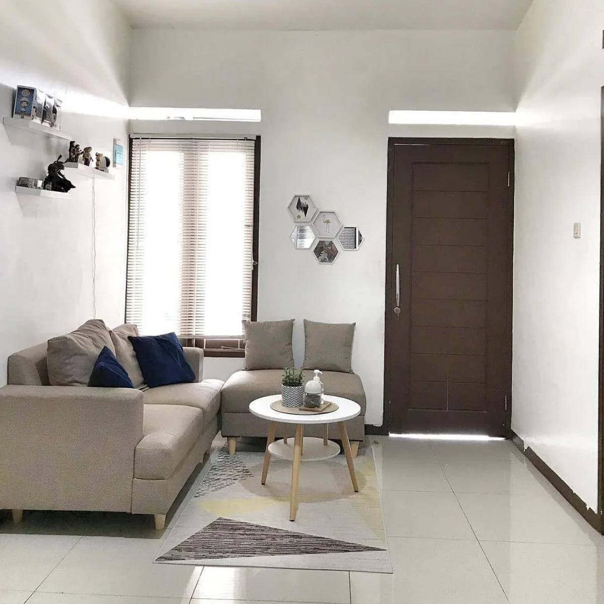 Ruang tamu minimalis dengan sofa beige, meja bulat putih, dan dinding putih bersih yang estetik.