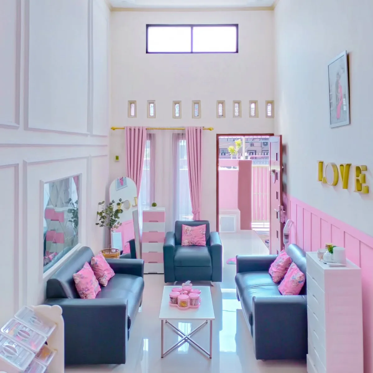Ruang tamu plafon tinggi mewah dengan kombinasi sofa hitam dan dekorasi pink serta dinding wainscoting.