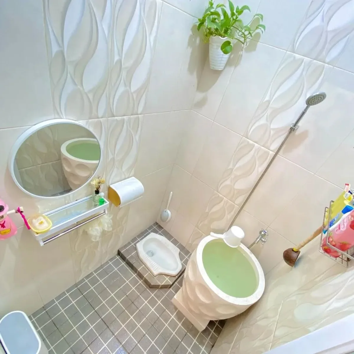 Tata letak desain kamar mandi minimalis modern 1.2 x 1.5 meter tampak atas, menggunakan dinding keramik motif gelombang, cermin bulat, dan tanaman hias gantung untuk suasana segar.