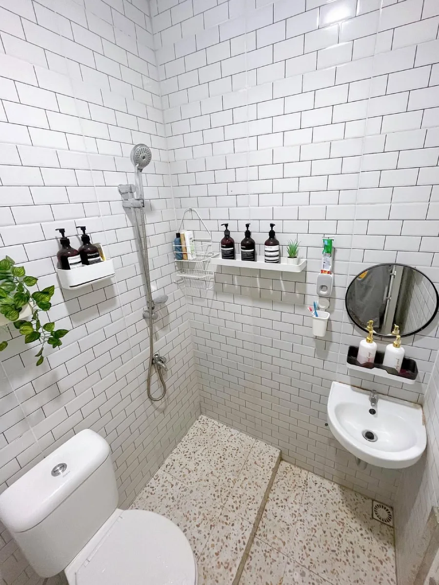 Inspirasi desain kamar mandi minimalis modern berukuran 1.5 x 1.5 meter dengan dinding keramik subway putih yang rapi, dilengkapi wastafel gantung dan area shower yang fungsional.