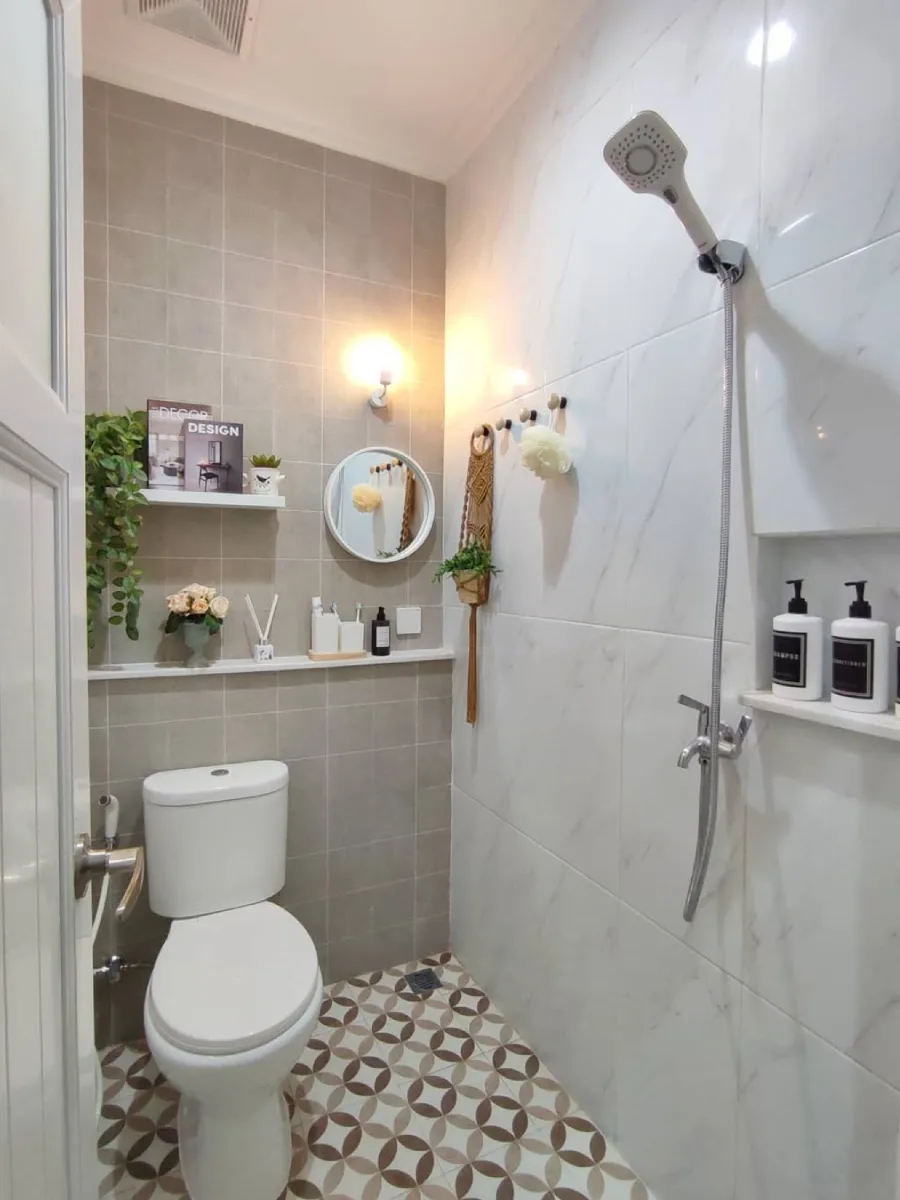 Inspirasi desain kamar mandi minimalis modern ukuran 1.15 x 1.75 meter dengan dinding keramik abu-abu dan putih, dilengkapi toilet duduk, shower area, serta dekorasi tanaman hijau yang memberikan kesan segar dan rapi.