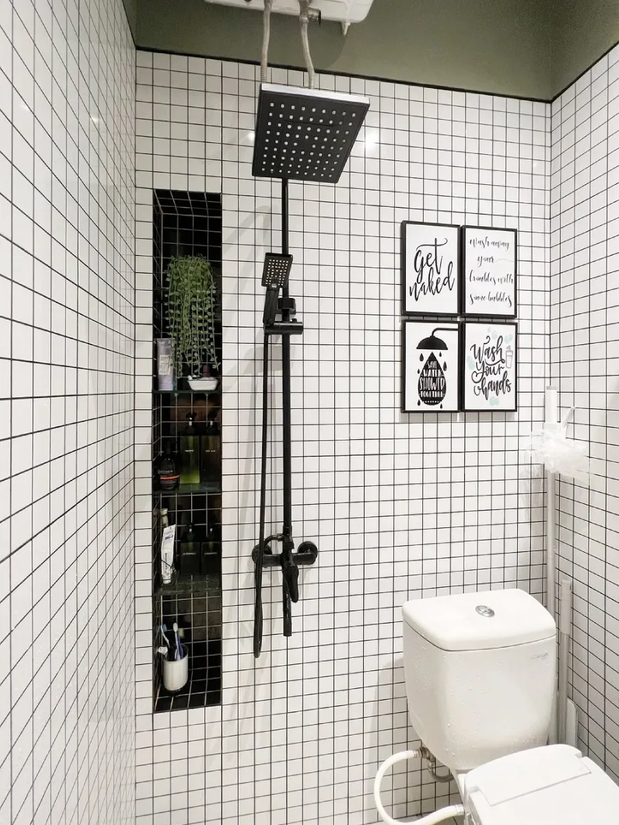 Desain kamar mandi minimalis modern 1.5 x 1.3 meter yang dilengkapi dengan shower hitam elegan, rak dinding tanam (niche), dan dekorasi dinding estetik di atas kloset duduk.