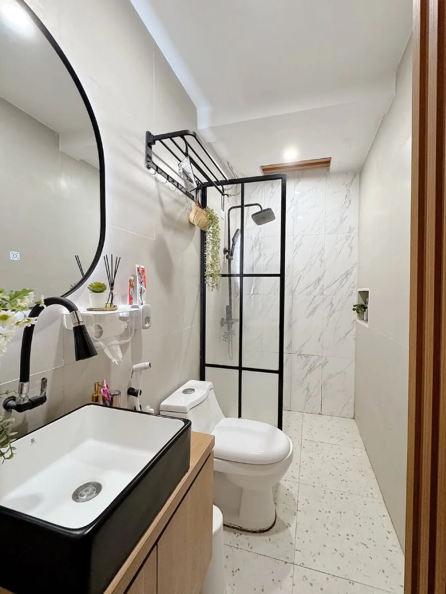 Tata letak desain kamar mandi minimalis memanjang 1.2 x 2.7 meter dengan konsep modern, menampilkan area shower dinding motif marmer, lantai terrazzo putih, dan pencahayaan lampu downlight yang hangat dan bersih.