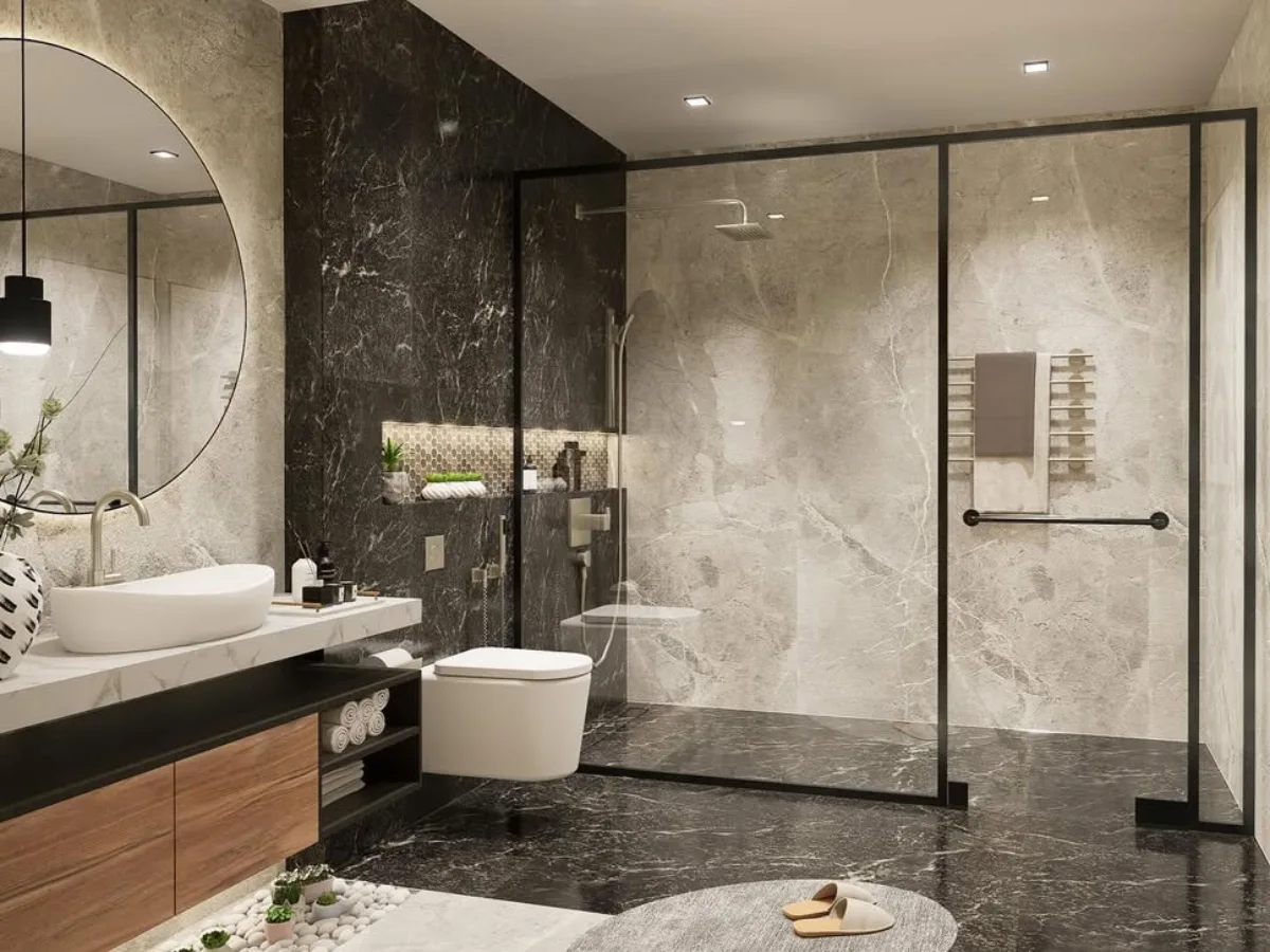 Sudut lain dari kamar mandi modern minimalis. Fokus pada partisi kaca shower dengan bingkai hitam tegas. Dinding dihiasi dua lukisan seni abstrak monokrom. Area wastafel memiliki pencahayaan hangat, dan lantai marmer hitam di area shower kontras dengan lantai abu-abu di area kering.