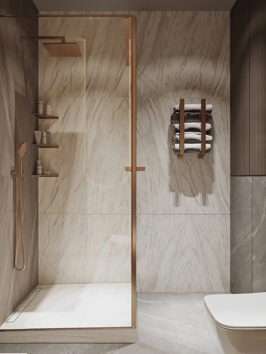 Area shower kamar mandi mewah dengan dinding marmer bermotif bookmatch, partisi kaca berbingkai tembaga (rose gold), set shower hujan warna senada, dan rak handuk dinding vertikal yang modern.