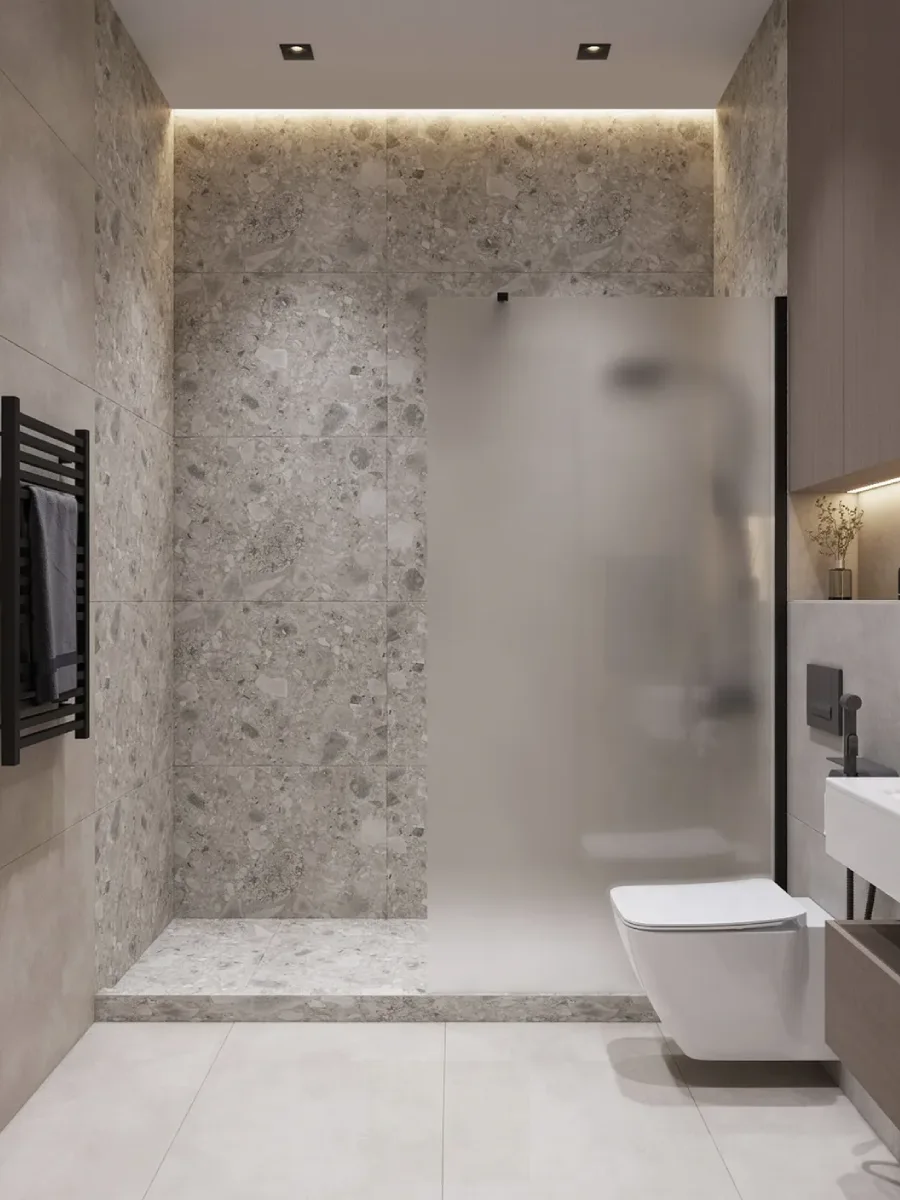 Tampilan partisi kaca buram (frosted glass) yang memisahkan area shower, dilengkapi gantungan handuk pemanas (towel warmer) hitam di dinding teraso.